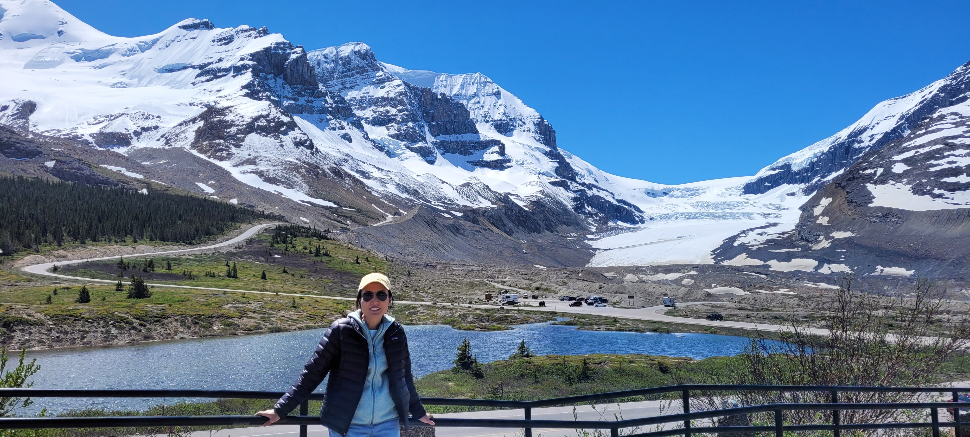 A woman in front of the columbia ice field in canada on a clear day